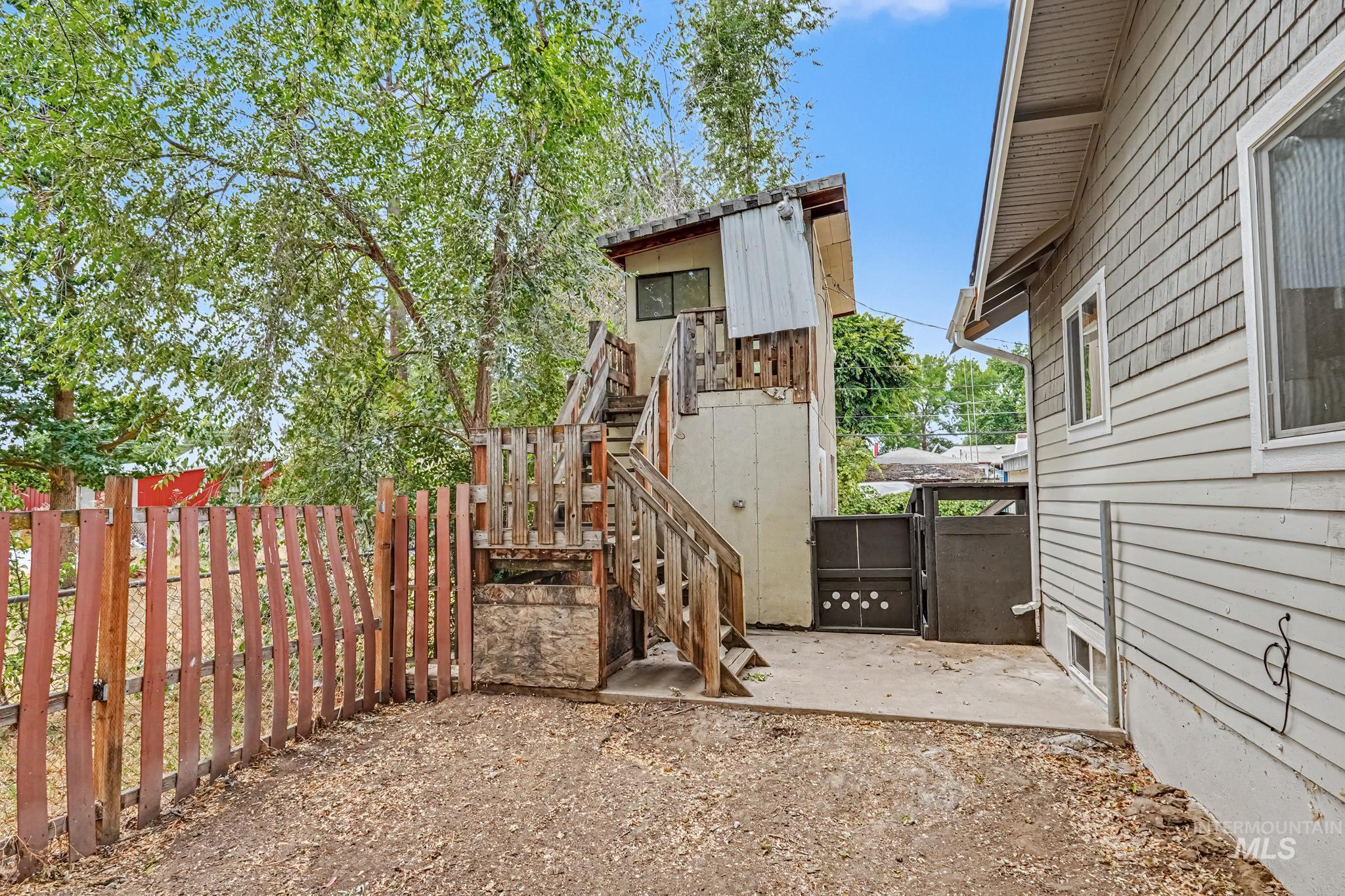 1023 State Street Weiser, ID 83672 - Photo 25 of 25 Rear exterior featuring a multi-level wooden deck with stairs, a concrete patio area, and a privacy fence