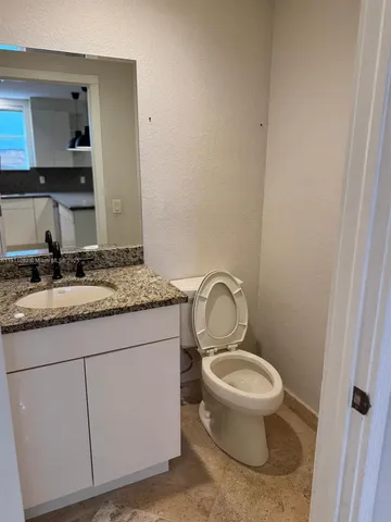 a bathroom with a granite countertop toilet sink and mirror
