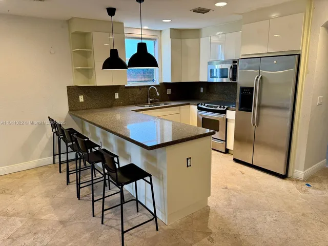 a kitchen with stainless steel appliances granite countertop a sink a stove and a refrigerator