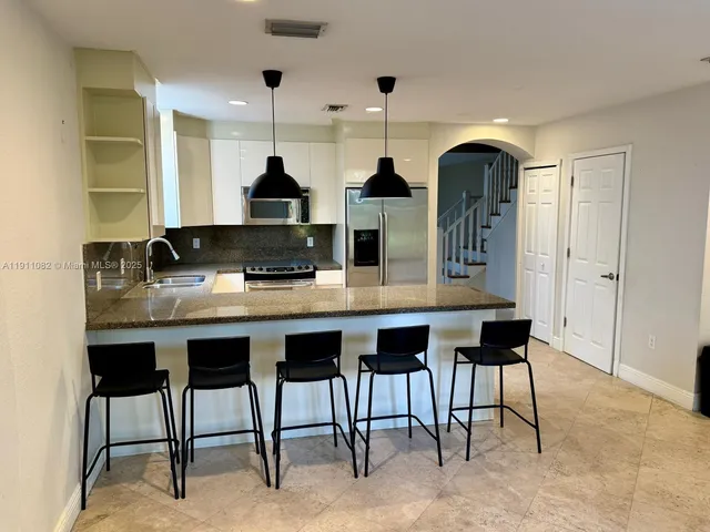 a kitchen with a sink and chairs