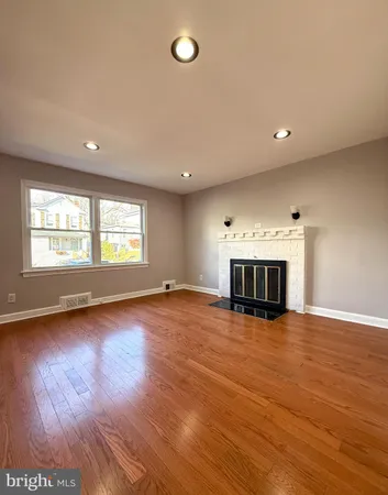 an empty room with wooden floor fireplace and windows