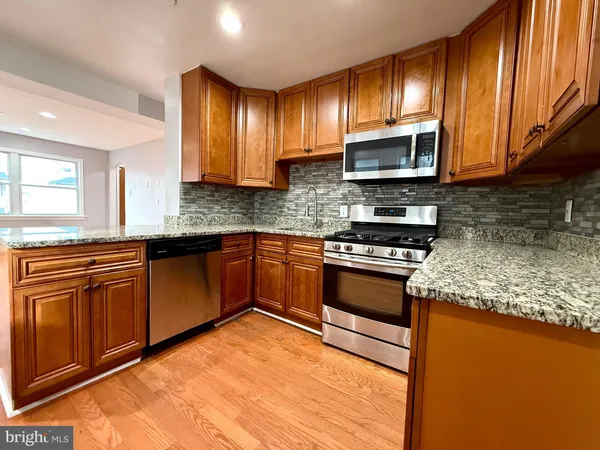 a kitchen with stainless steel appliances granite countertop wooden cabinets a stove top oven a sink and dishwasher