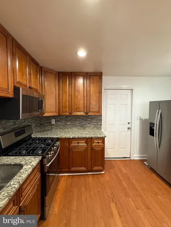 a kitchen with stainless steel appliances granite countertop a stove a sink dishwasher and a refrigerator with wooden floor