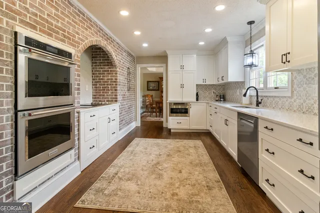 a large kitchen with stainless steel appliances kitchen island granite countertop a stove and a sink
