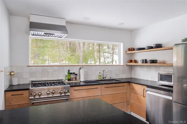 a kitchen with stainless steel appliances granite countertop a sink a stove and a refrigerator