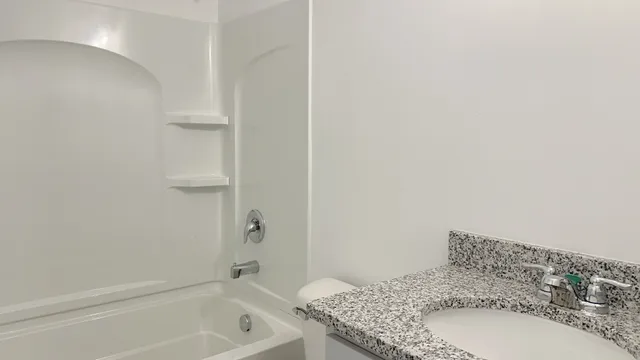 a bathroom with a granite countertop sink and a bathtub