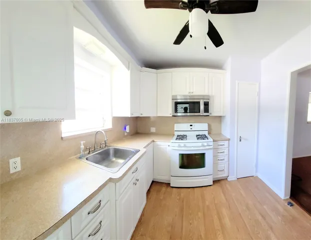 a kitchen with stainless steel appliances granite countertop a sink and a stove with white countertops