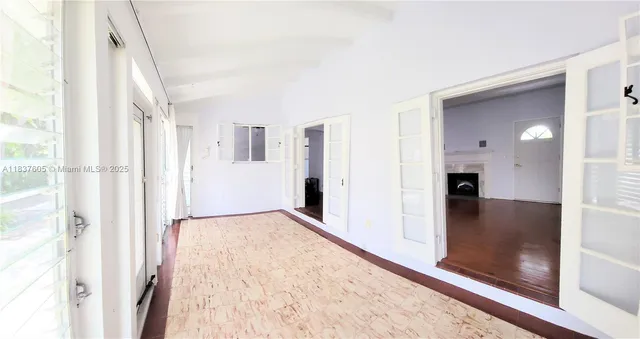a view of a hallway with wooden floor and a bathroom