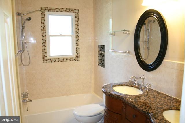 6021 Craft Road Alexandria, VA 22310 - Photo 26 of 30 a bathroom with a granite countertop sink a mirror a bathtub and a shower