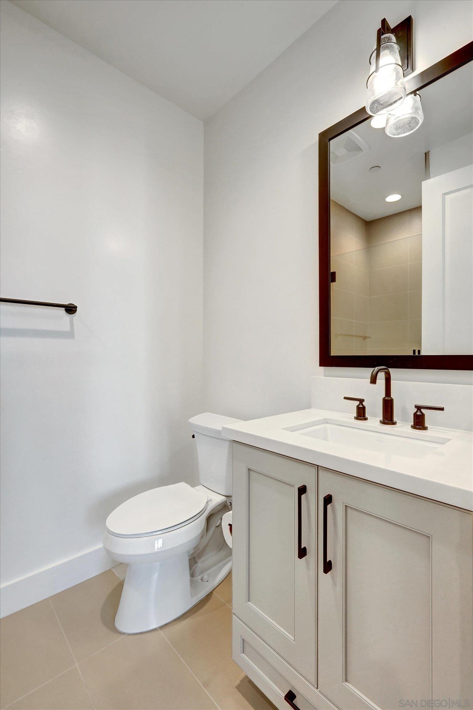 1602 Pl Encinitas Ca, Unit 104 Encinitas, CA 92024 - Photo 11 of 22 a bathroom with a toilet a sink and mirror