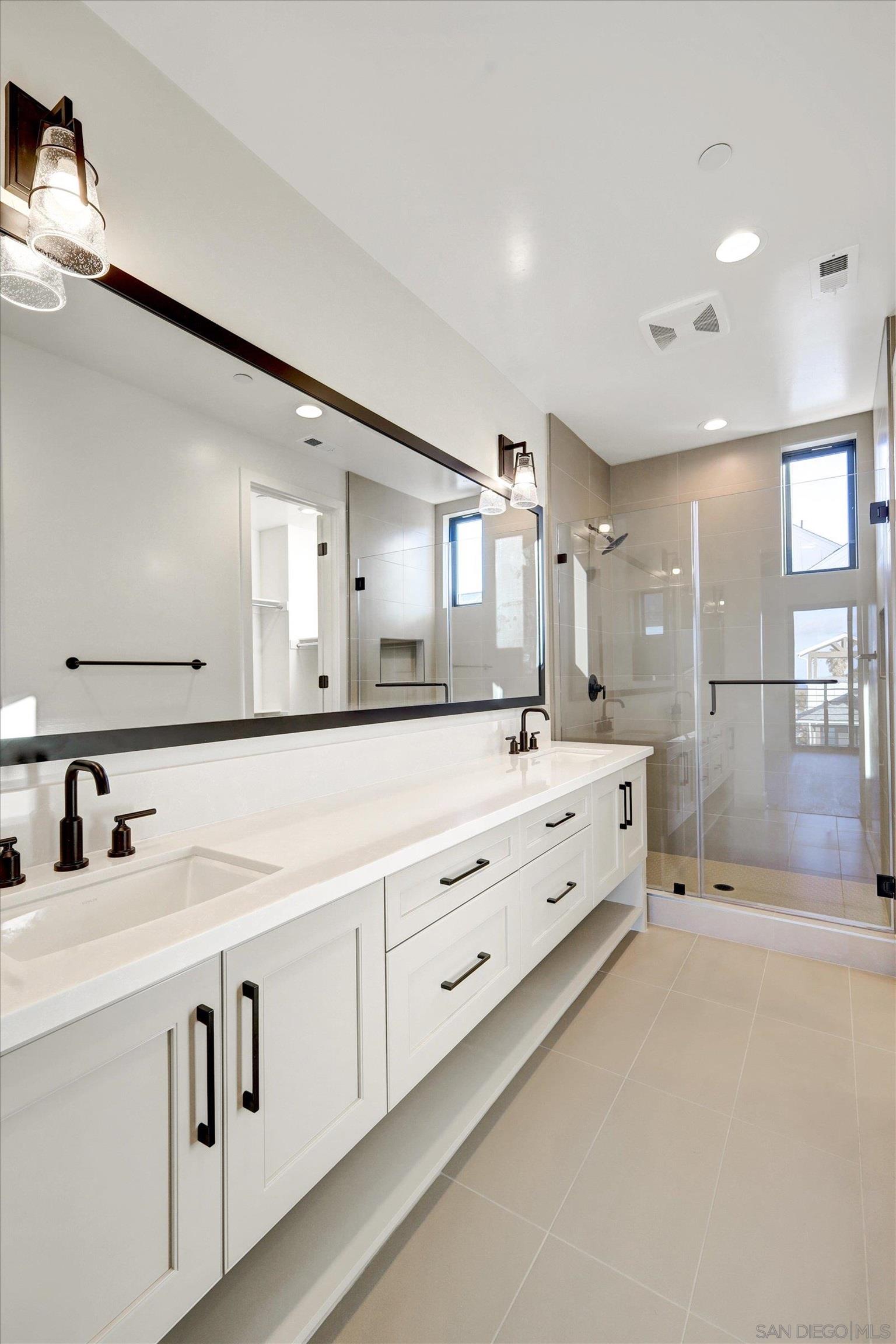 1602 Pl Encinitas Ca, Unit 104 Encinitas, CA 92024 - Photo 8 of 22 a large bathroom with a large mirror vanity and shower