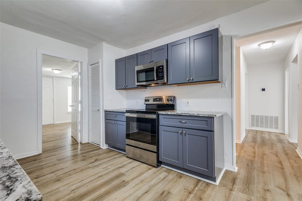 217 Ridgeway Avenue Azle, TX 76020 - Photo 11 of 27 a kitchen with granite countertop wooden floors and stainless steel appliances
