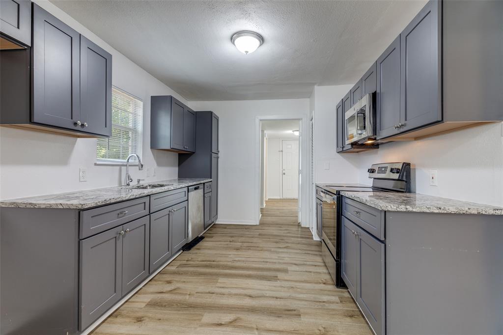 217 Ridgeway Avenue Azle, TX 76020 - Photo 12 of 27 a kitchen with stainless steel appliances granite countertop wooden cabinets a sink and dishwasher