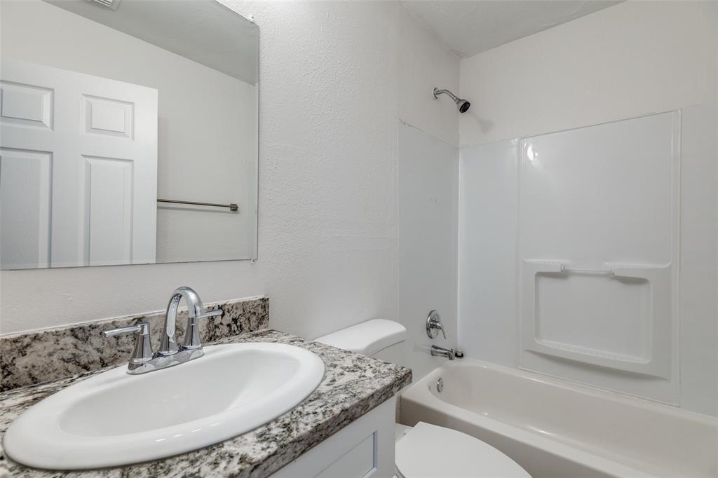 217 Ridgeway Avenue Azle, TX 76020 - Photo 16 of 27 a bathroom with a granite countertop sink a toilet and shower
