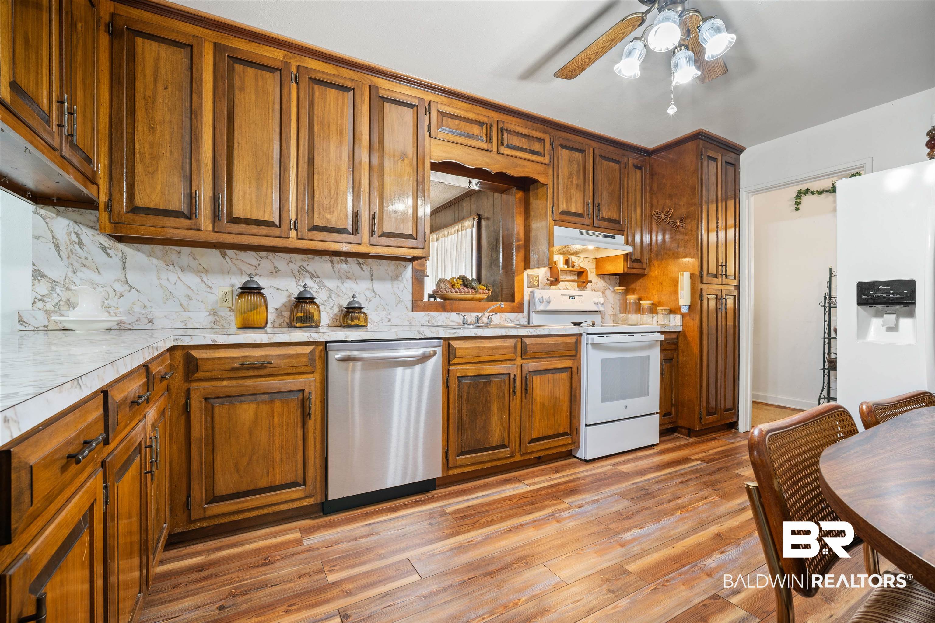 2618 Serigny Drive Mobile, AL 36605 - Photo 6 of 25 Kitchen featuring brown cabinetry, white appliances, light countertops, a ceiling fan, and under cabinet range hood