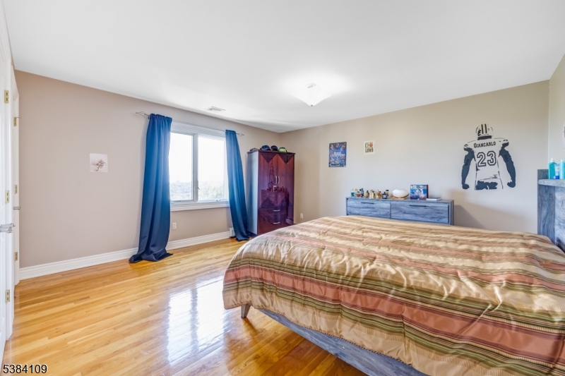 207 Eileen Drive Cedar Grove, NJ 07009 - Photo 18 of 26 a bedroom with a large bed and a chandelier