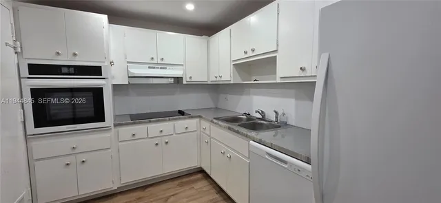 a kitchen with granite countertop white cabinets and white appliances