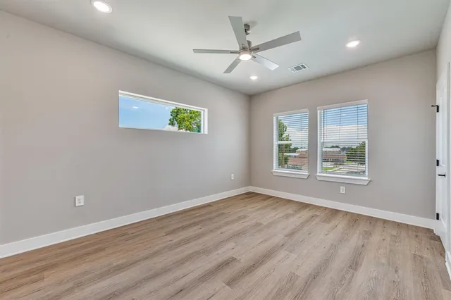 a view of an empty room with a window and wooden floor