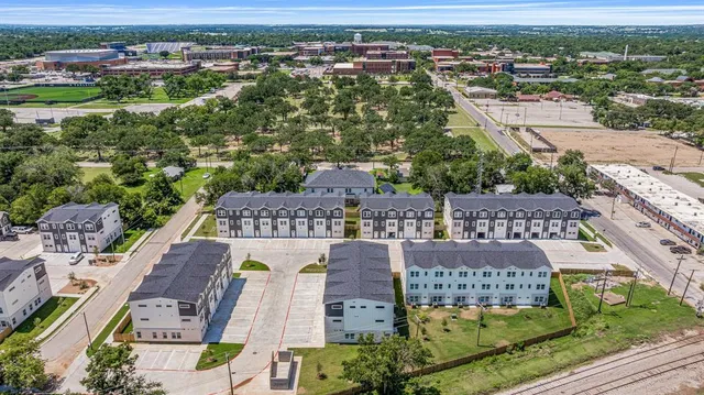 an aerial view of residential houses with outdoor space and parking
