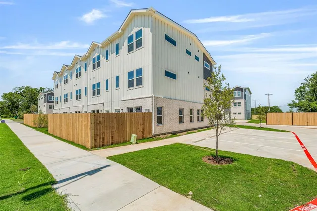 a view of a white building with a yard