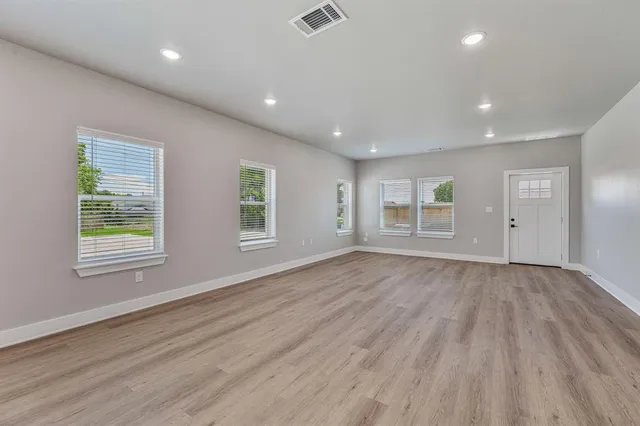 an empty room with wooden floor and windows