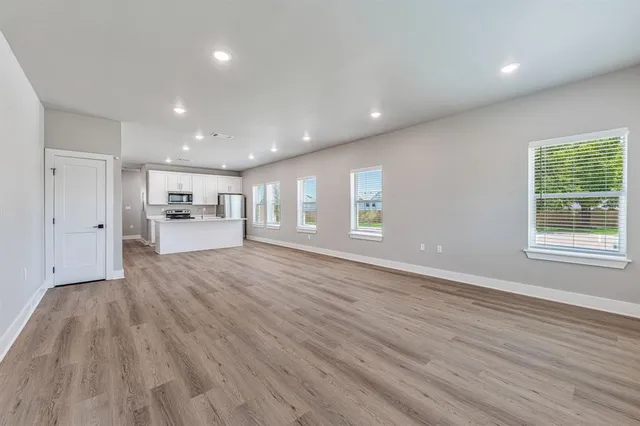 a view of empty room with kitchen and window