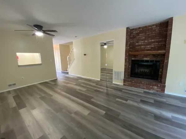 a view of an empty room with wooden floor fireplace and a window