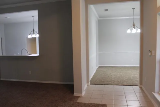 a view of an empty room with chandelier and fireplace
