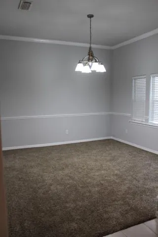 a view of a livingroom with a fireplace a chandelier and windows
