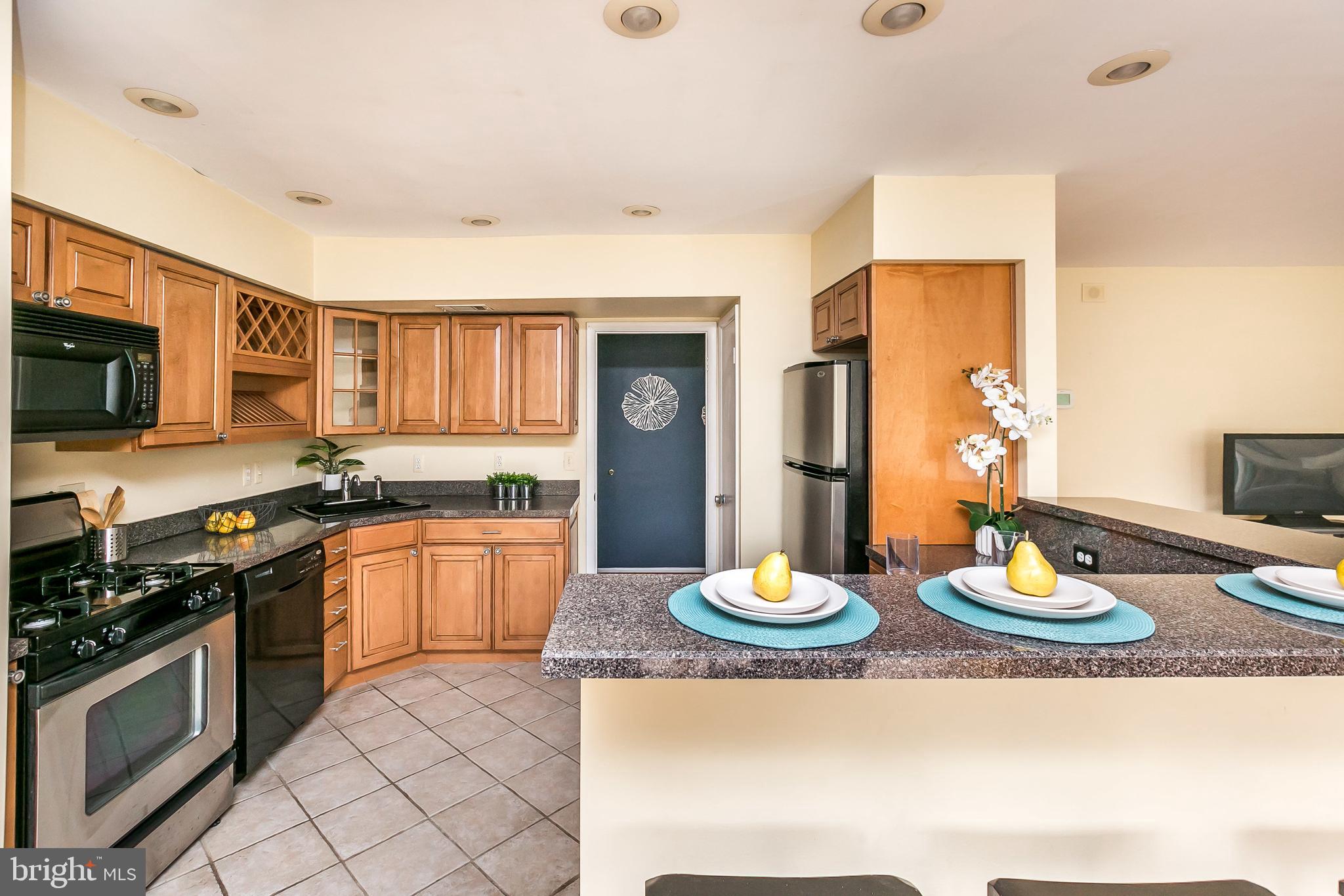 114 Cross Keys Road, Unit R114E Baltimore, MD 21210 - Photo 12 of 33 a kitchen with stainless steel appliances kitchen island granite countertop a refrigerator a stove a sink and dishwasher with wooden floor