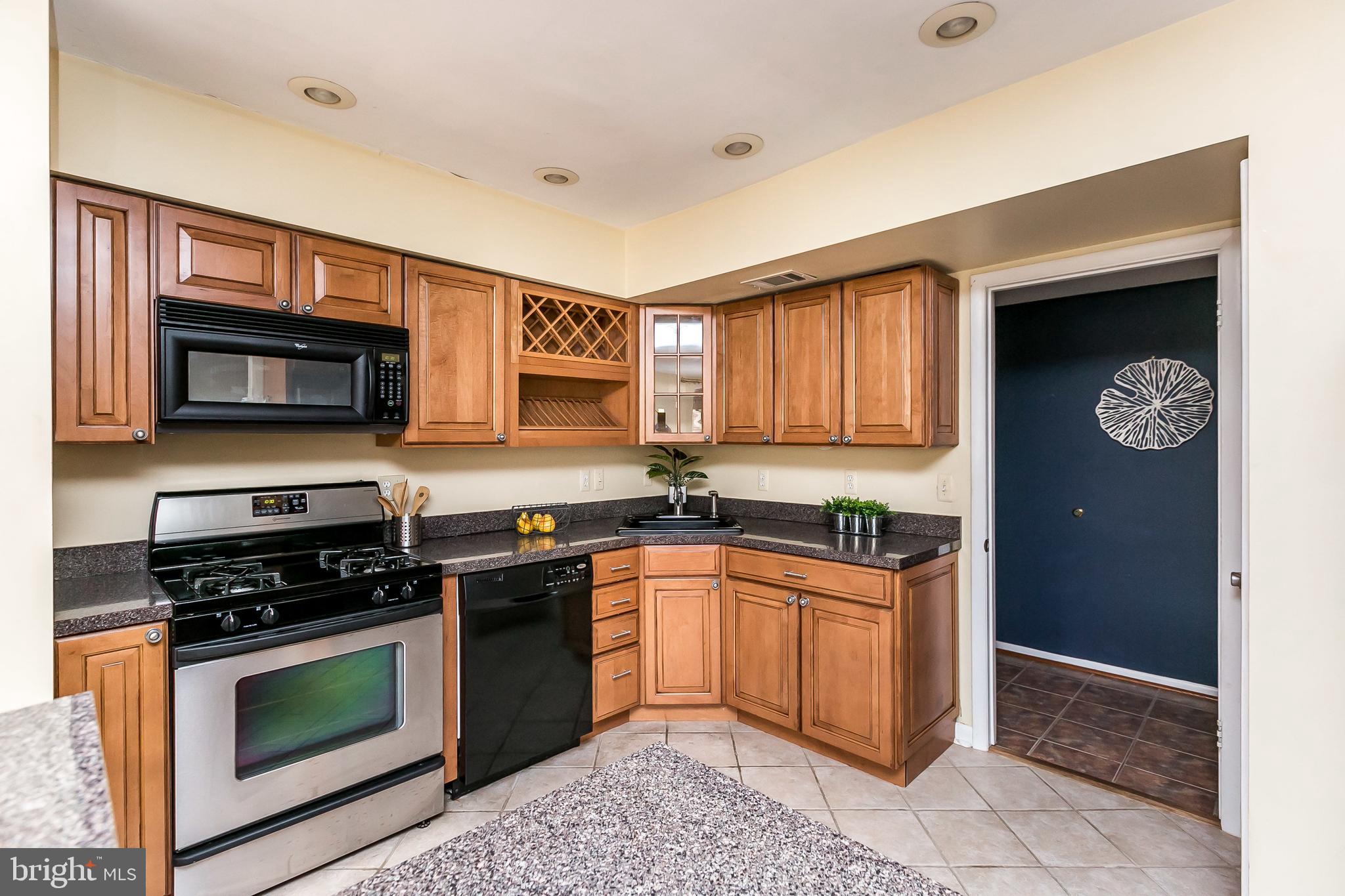 114 Cross Keys Road, Unit R114E Baltimore, MD 21210 - Photo 14 of 33 a kitchen with stainless steel appliances granite countertop a stove top oven a sink dishwasher and a microwave oven on the blue kitchen countertops