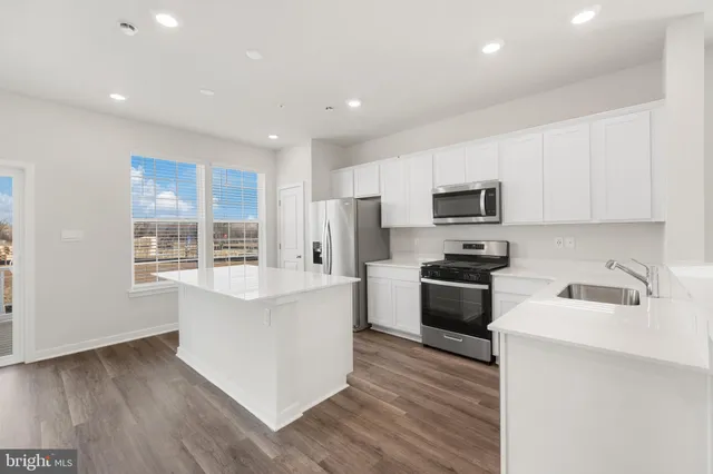 a kitchen with a sink wooden floor and stainless steel appliances