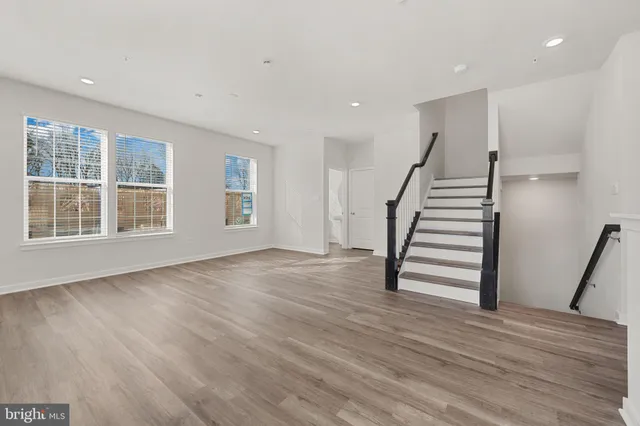 a view of an empty room with wooden floor and stairs