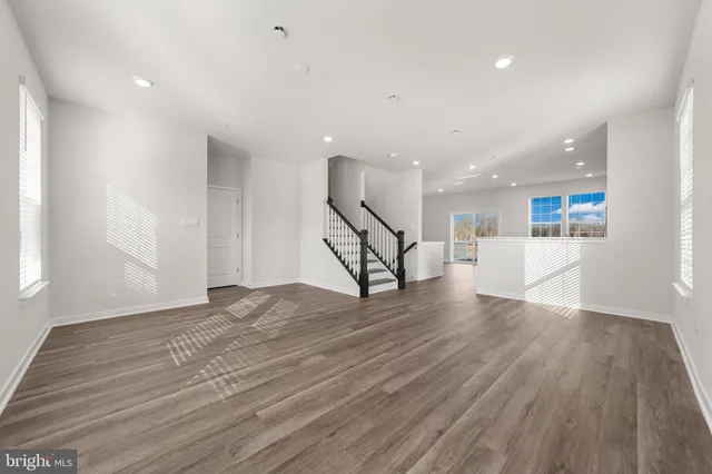 a view of an empty room with wooden floor and stairs