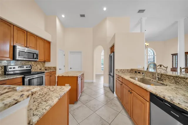 a kitchen with granite countertop stainless steel appliances a refrigerator stove top oven and sink