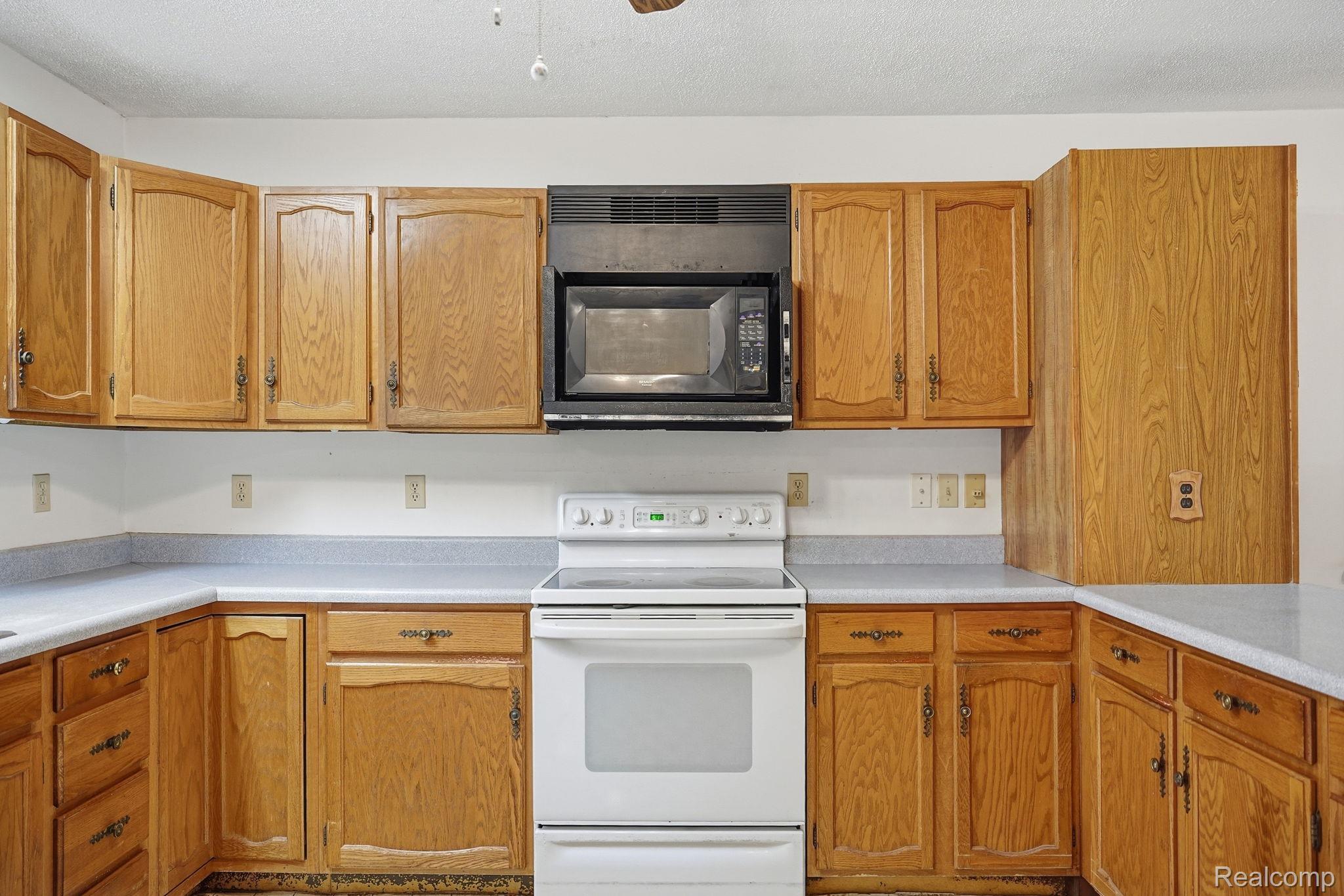 2259 Kassuba Road Gaylord, MI 49735 - Photo 16 of 46 U-shaped kitchen featuring wood cabinetry, light-toned countertops, a built-in microwave, and a freestanding electric range