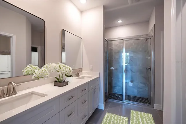 a bathroom with a granite countertop sink a toilet a mirror and shower