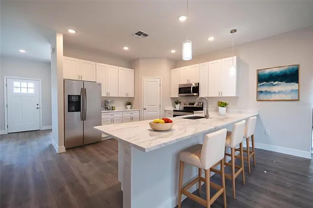 a view of an empty room with wooden floor and fan