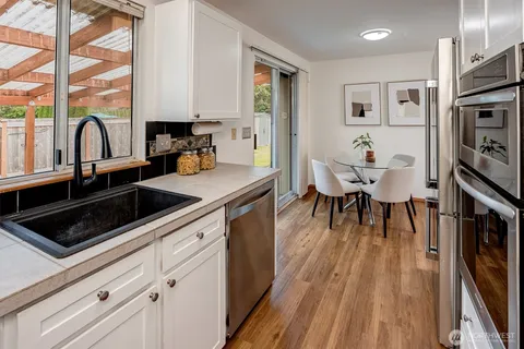 a kitchen with granite countertop a stove a sink a dining table and chairs