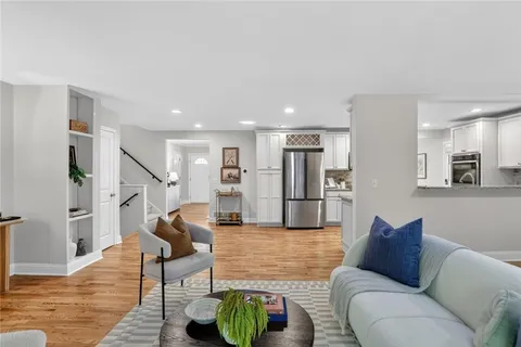 a living room with furniture wooden floor and a kitchen view