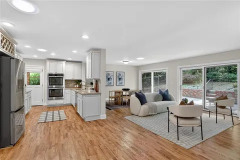 a living room with furniture wooden floor and a kitchen view