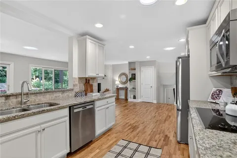 a kitchen with stainless steel appliances granite countertop a sink stove and cabinets