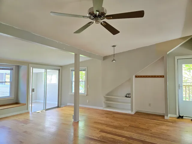 a view of an empty room with window and wooden floor