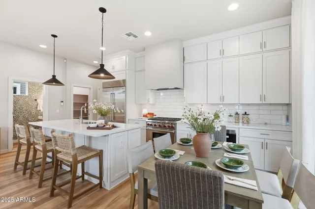 a kitchen with a stove a white cabinets and chairs