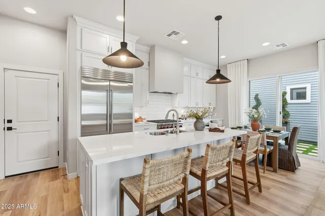 a kitchen with stainless steel appliances a table chairs and white cabinets