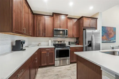 a kitchen with stainless steel appliances kitchen island granite countertop a sink refrigerator and cabinets