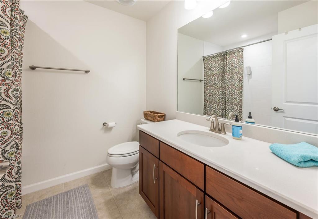 4720 Arboretum Circle, Unit 102 Naples, FL 34112 - Photo 23 of 44 a bathroom with a granite countertop sink a toilet and a mirror