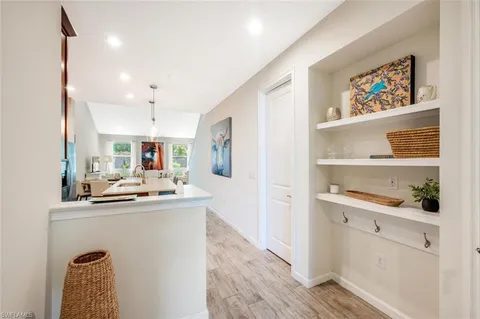 a view of a hallway with wooden floor and a refrigerator