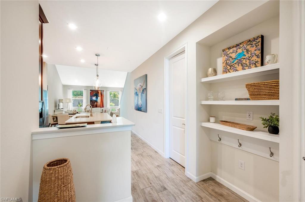 4720 Arboretum Circle, Unit 102 Naples, FL 34112 - Photo 4 of 44 a kitchen with kitchen island a sink a stove cabinets and wooden floor