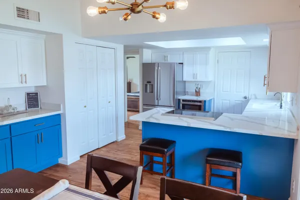 a kitchen with stainless steel appliances kitchen island granite countertop a refrigerator cabinets and wooden floor